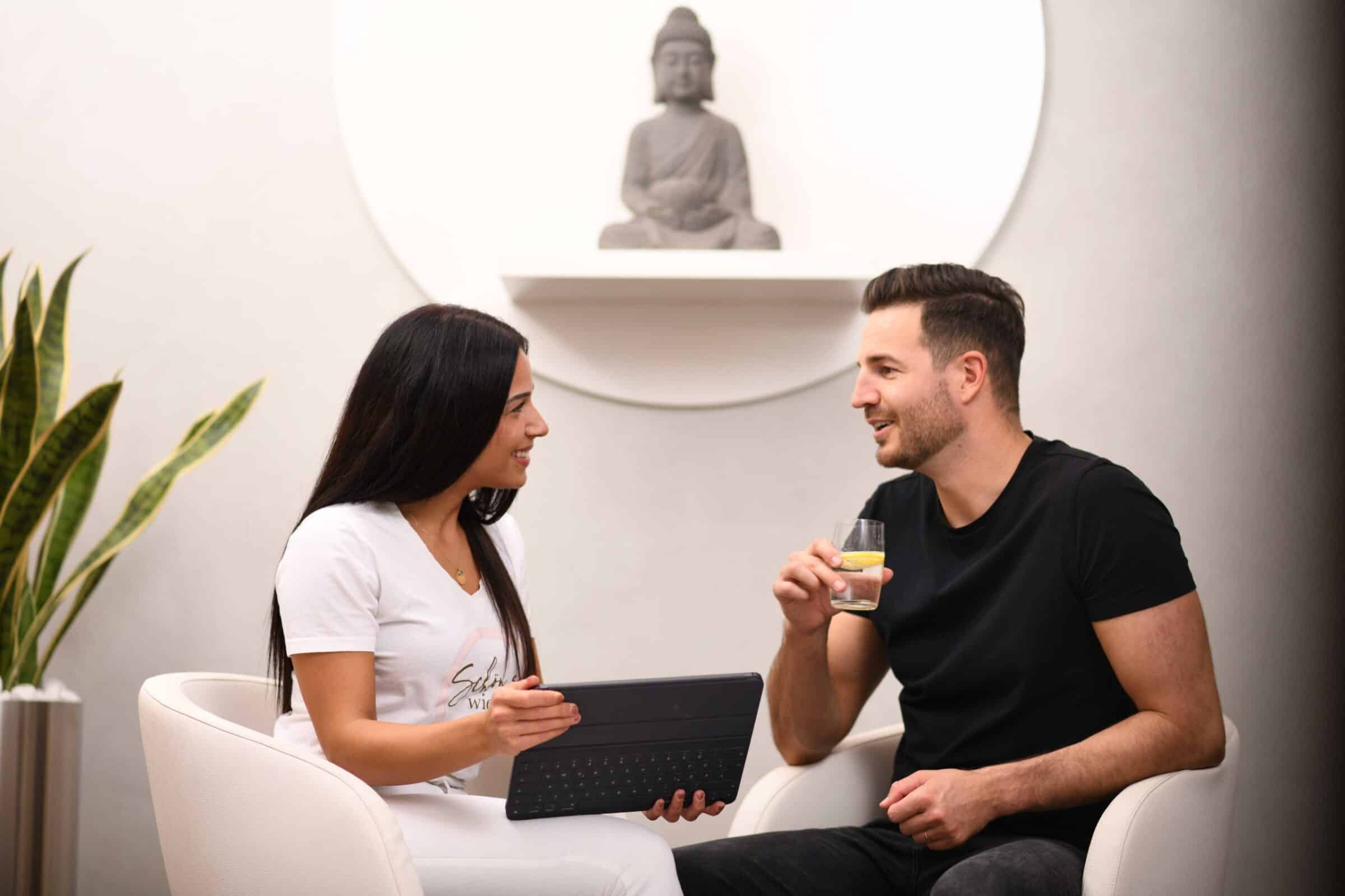 Mitarbeiterin berät einen Kunden in entspannter Atmosphäre zu Gesundheits- und Wellnessangeboten.